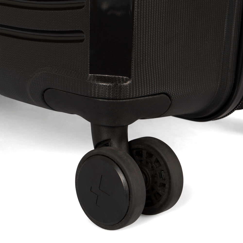 Close up view of a black luggage called Dynamo designed by Tracker showing 1 of 4 spinner wheels with the tracker logo on it.