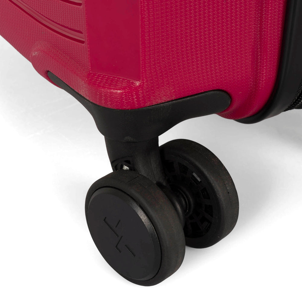 Close up view of a red luggage called Dynamo designed by Tracker showing  1 of 4 spinner wheels with the tracker logo on it.