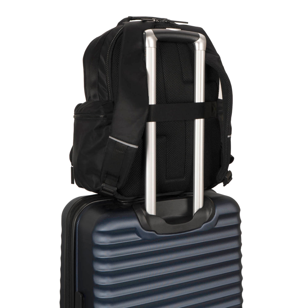 Backside view of a black backpack called Sutton by Tracker on a luggage, showcasing its luggage strap attached to a luggage handle.