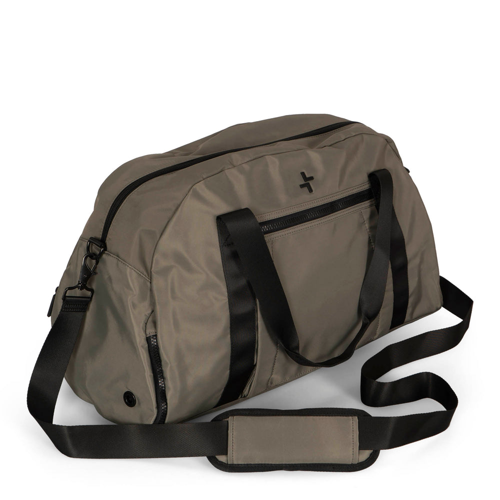 Angle view of a grey-green duffle bag called Sutton designed by Tracker on a white background, showcasing its top handle, main zipper compartment, front zipper pocket and 1 side zipper pocket, and removable strap.