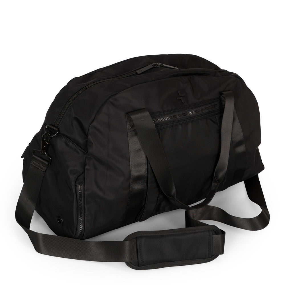 Angle view of a black duffle bag called Sutton designed by Tracker on a white background, showcasing its top handle, main zipper compartment, front zipper pocket and 1 side zipper pocket, and removable strap.