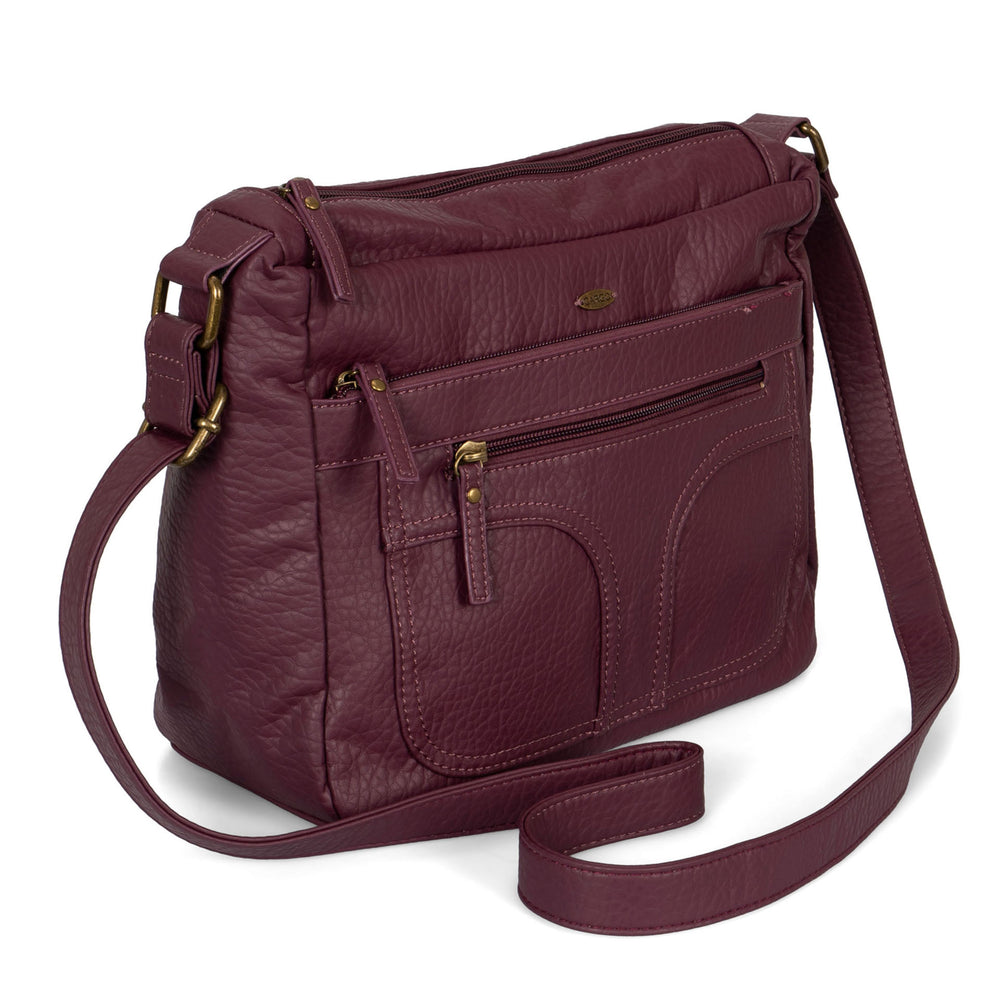 Angle view of a women's burgundy crossbody bag called Pebbled from the brand Cargo on a white background, showcasing its zippers, soft texture, and strap.